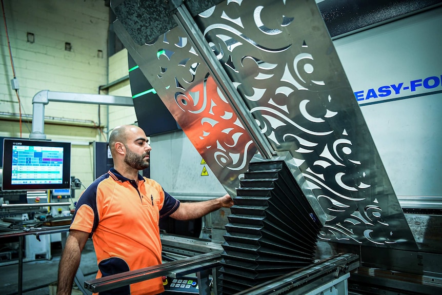 A man working on a steel fabrication sheet in a factory