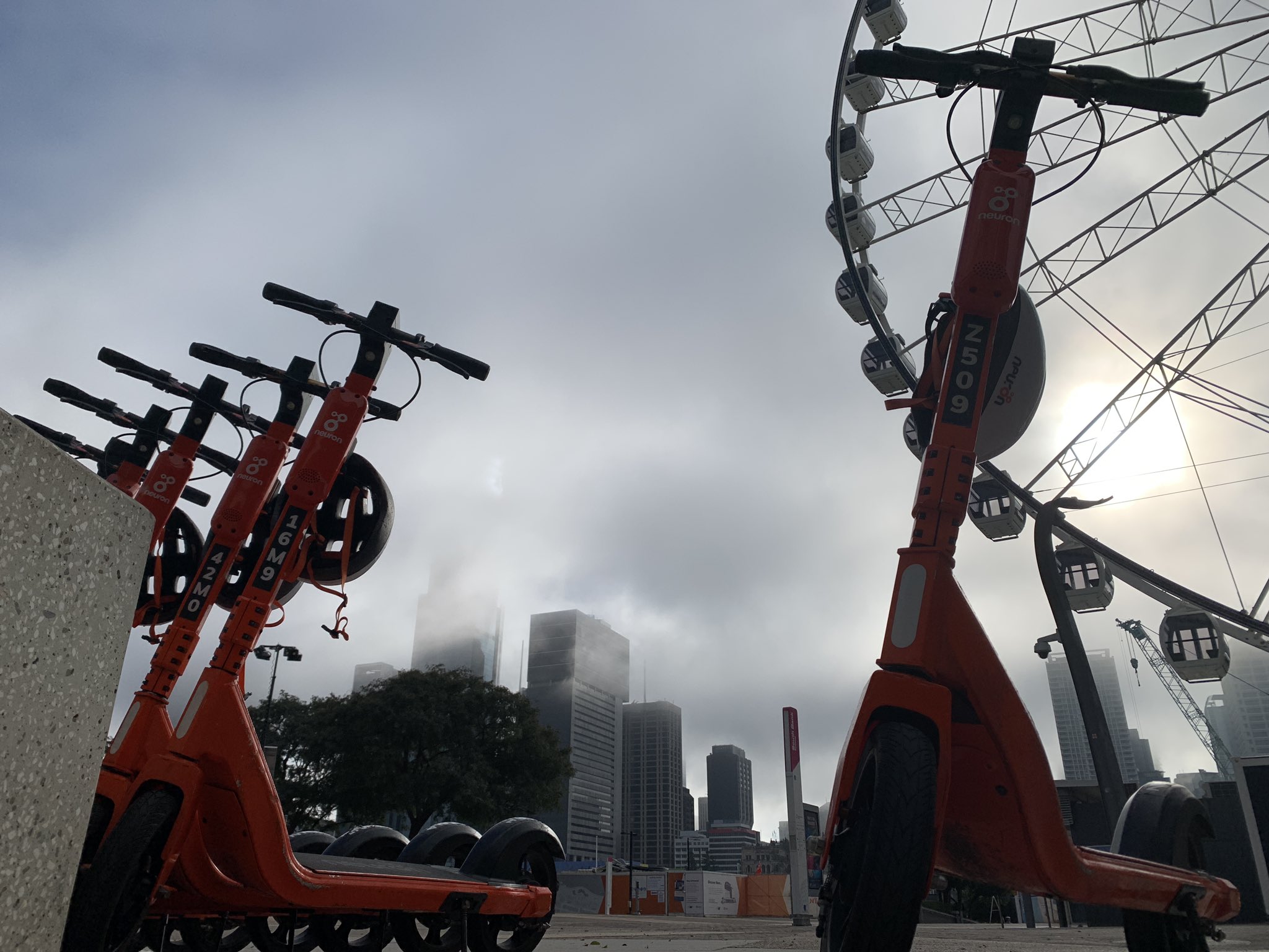 Foggy Southbank with scooters in the foreground and the Wheel of Brisbane behind.