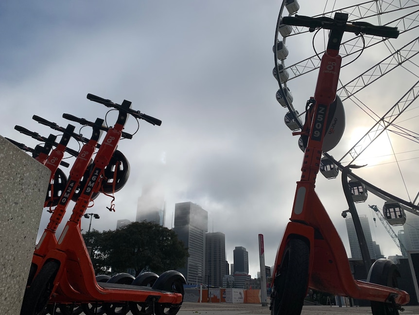 Foggy Southbank with scooters in the foreground and the Wheel of Brisbane behind.