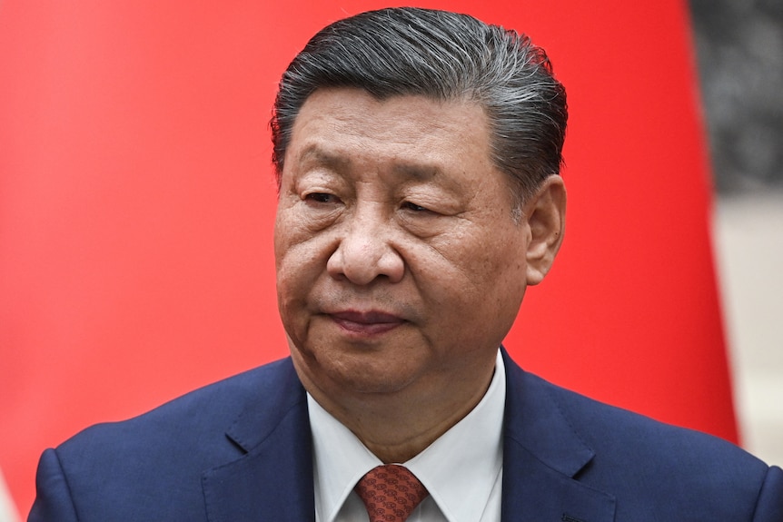 A close up of Xi Jinping looking over his shoulder while wearing a suit.