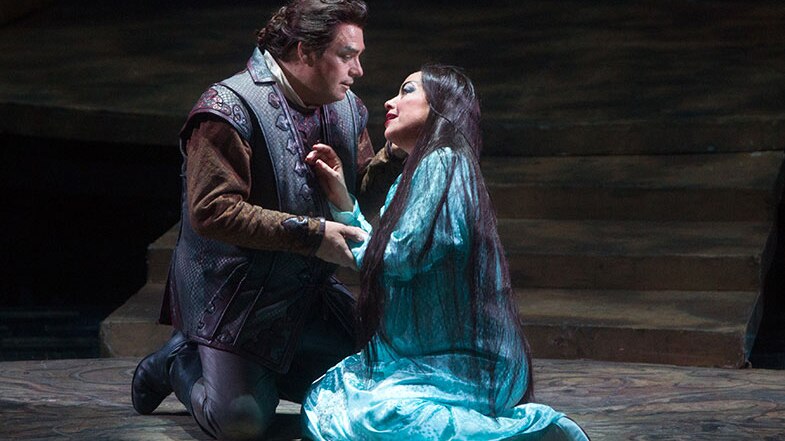 Two characters in Turandot kneel on the floor in a half embrace.