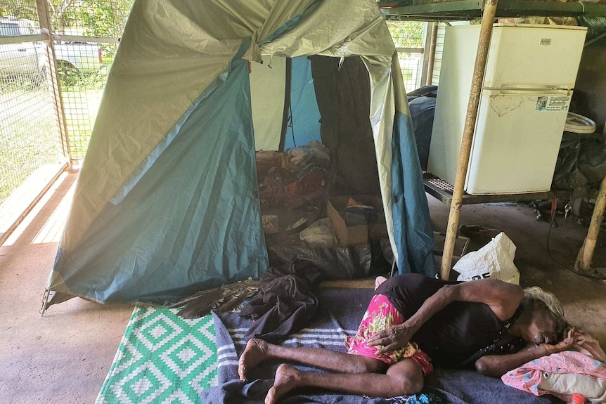 Mary Dadbalag laying next to her tent, it is inside fences walls.