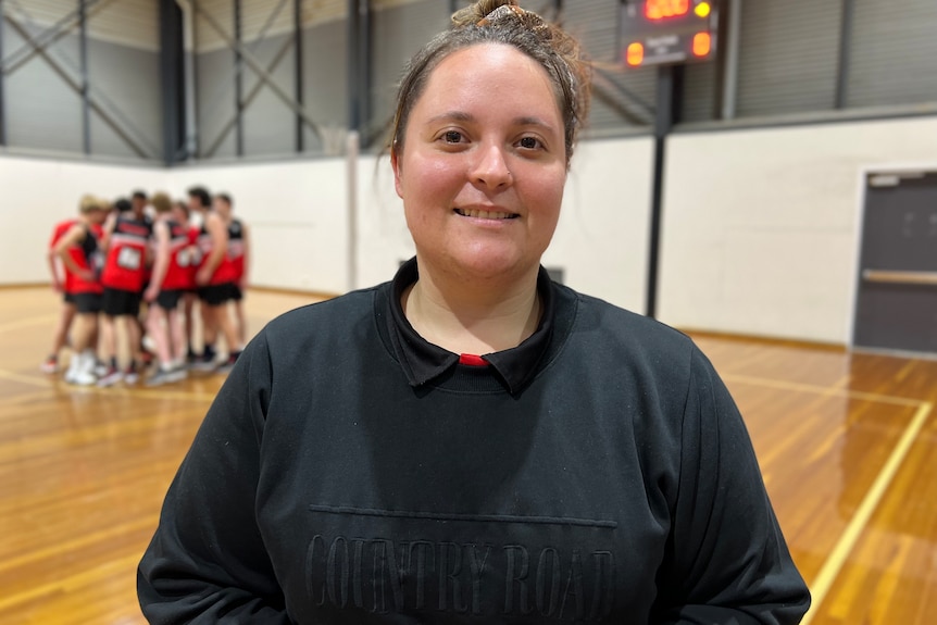 Brie Dejong wears a black jumper with a brown top knot, in the background the waverly team is huddled