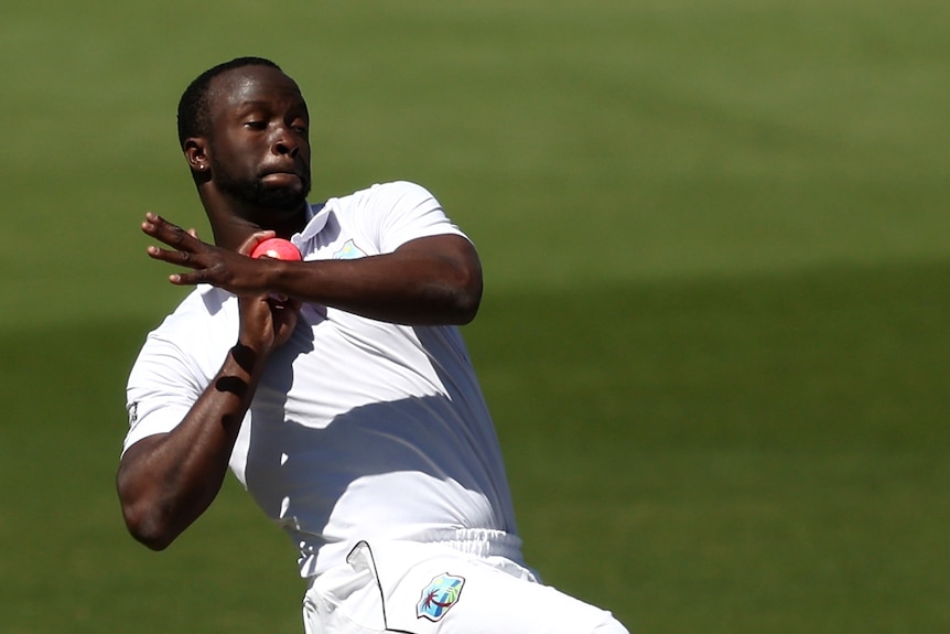 Kemar Roach holds the ball in a cocked position preparing to bowl in his delivery stride.