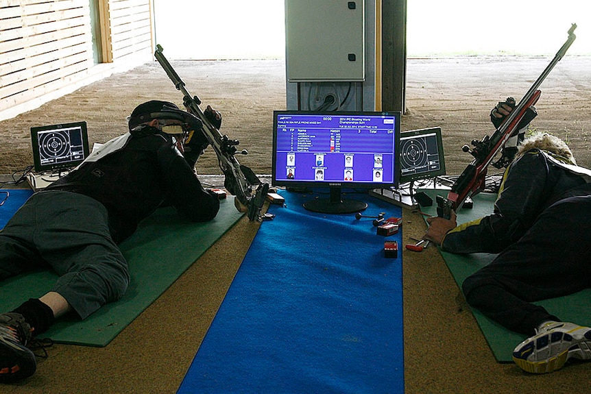 Two men lying down with guns on a shooting range.