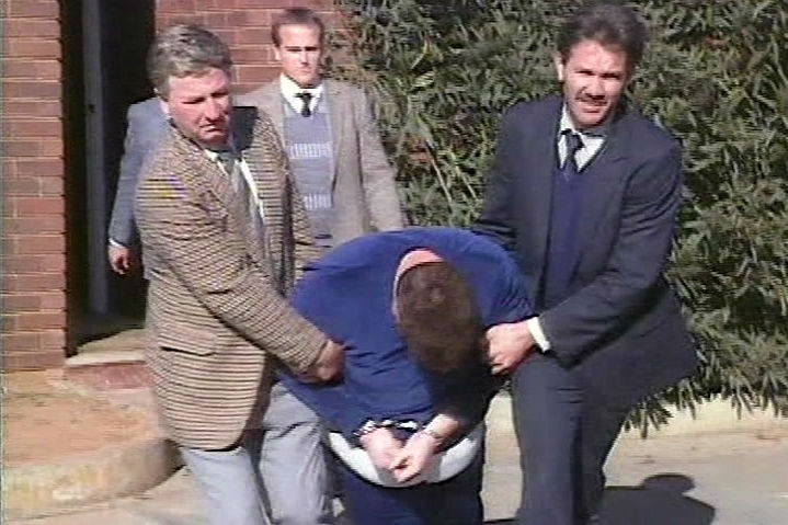 Police officers drag Craig Minogue to a police car.