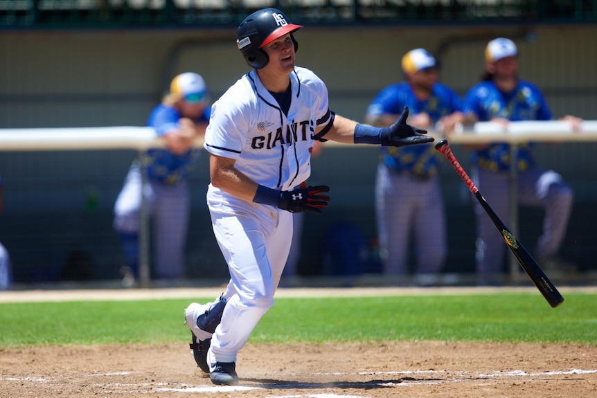 An Australian male baseball player watches the ball after hitting while batting in the ABL.