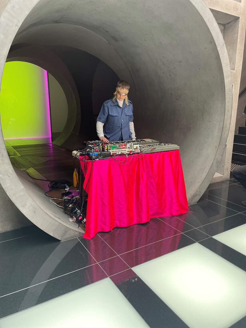 A DJ stands at a table inside a concrete tunnel.