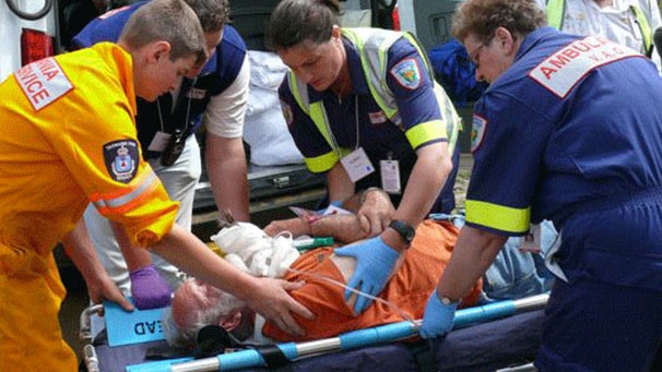 Ambulance Tasmania staff attend to person on gurney near ambulance.