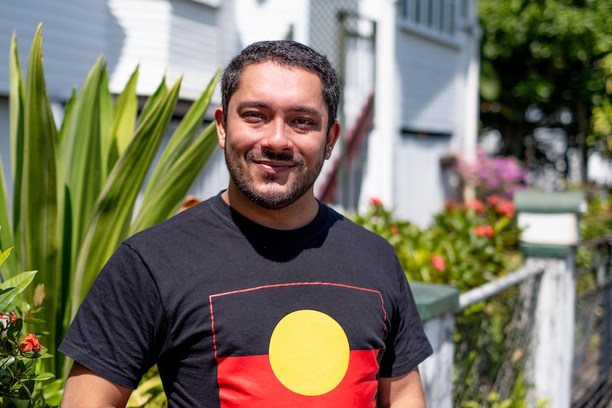 A man with short hair wearing an Aboriginal flag t-shirt