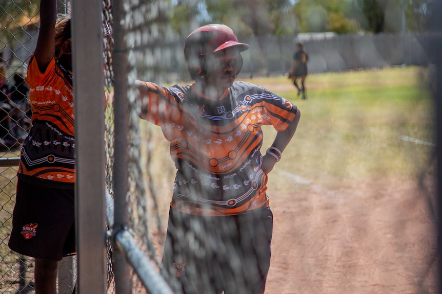 A woman wearing a softball helmet prepares to bat.