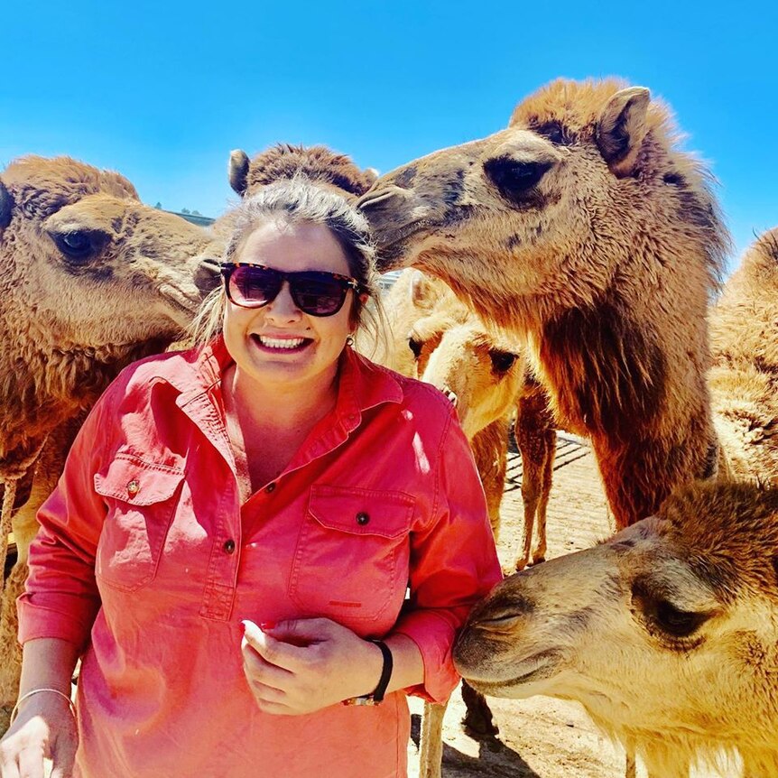 a woman with sunglasses with camels close by her