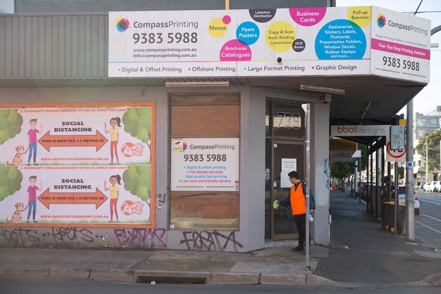 Banners promoting social distancing cover the side of the Compass Printing corner store front
