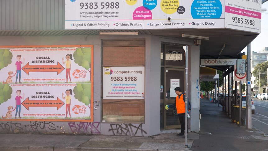 Banners promoting social distancing cover the side of the Compass Printing corner store front