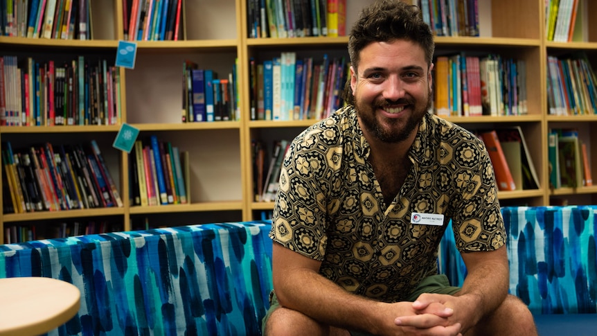 A man sits looking at the camera in a school library in Katherine.