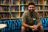 A man sits looking at the camera in a school library in Katherine.