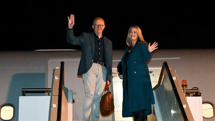 Australian Prime Minister Anthony Albanese and partner Jodie Haydon standing and waving as they board the plane.