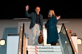 Australian Prime Minister Anthony Albanese and partner Jodie Haydon standing and waving as they board the plane.