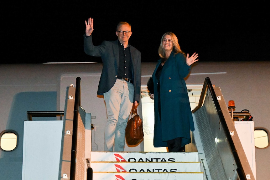 Australian Prime Minister Anthony Albanese and partner Jodie Haydon standing and waving as they board the plane.