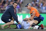 Medical staff attend to Shaun Fensom, who is prone on the turf.