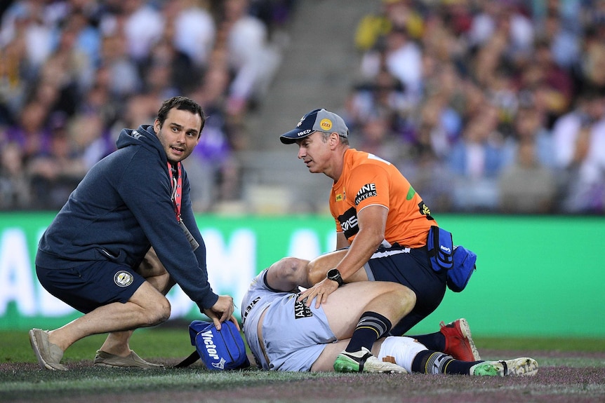 Medical staff attend to Shaun Fensom, who is prone on the turf.