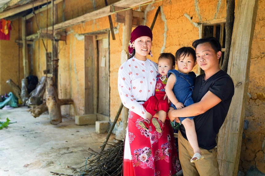 Mai, carrying one of her daughter, with her husband carrying their elder daughter.