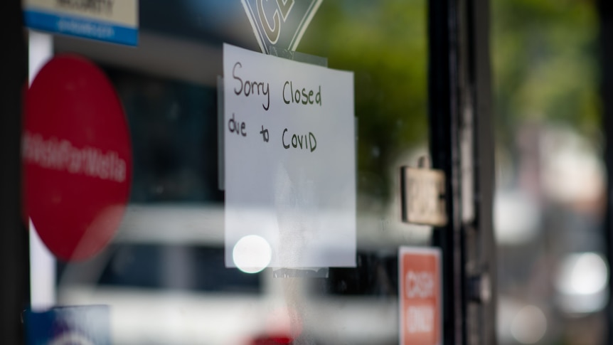 A photo of a sign on a shopfront saying: "Sorry, closed due to COVID".
