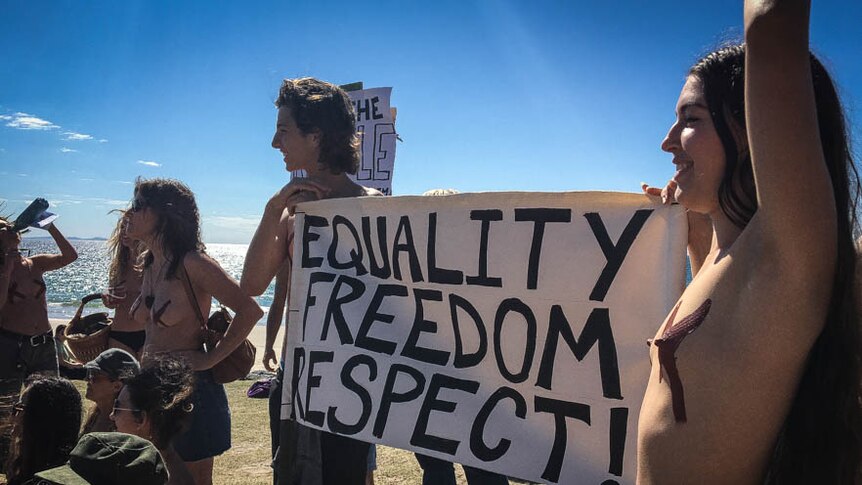 Topless people holding a sign that says equality, freedom and respect