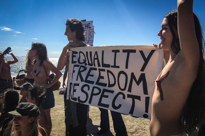 Topless people holding a sign that says equality, freedom and respect