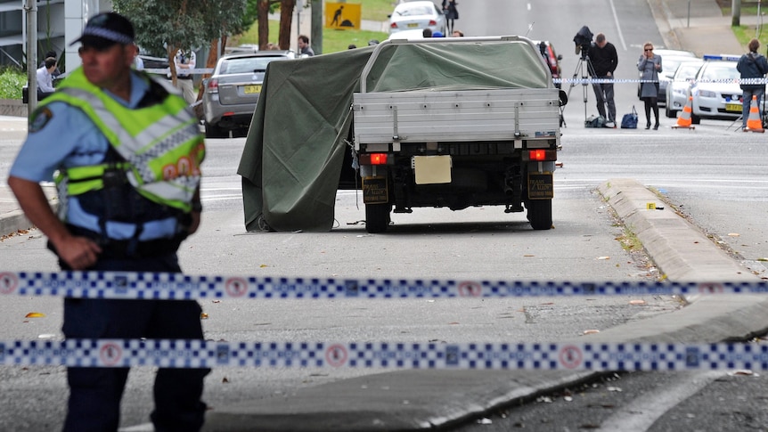 A police officer stands near a ute involved in a fatal shooting outside Castle Hill police station on September 29, 2011.
