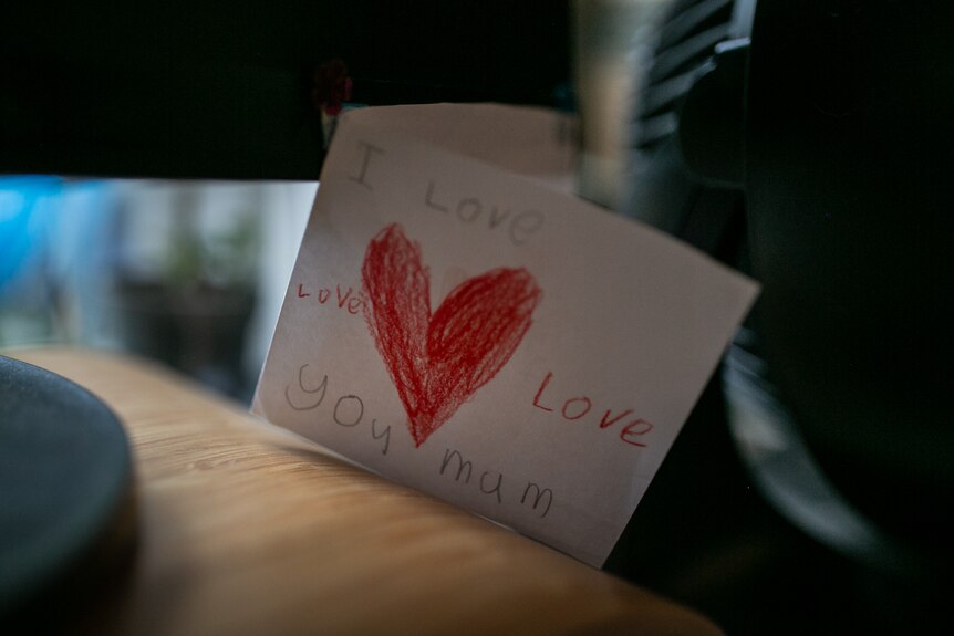 A handmade card with 'I love you mum' written on it and a red love heart.