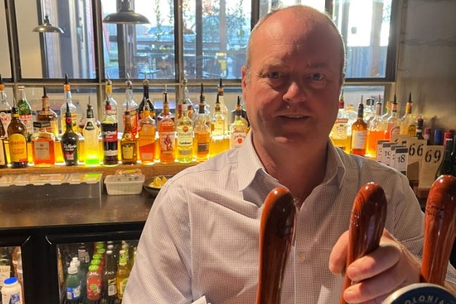 A man behind a bar pulling beers.