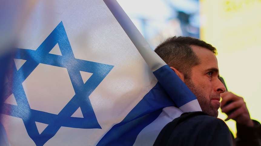 A man looks emotional as he holds as Israel flag