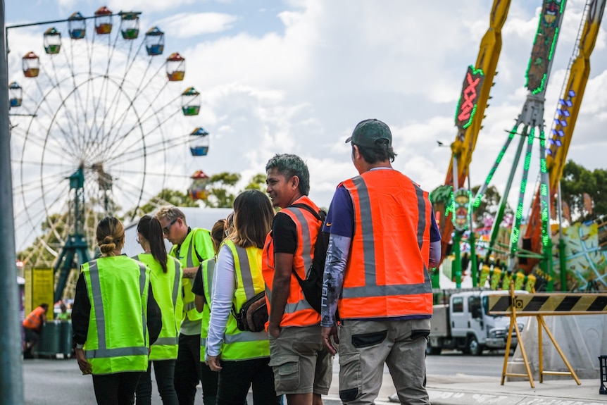 Group of workers in high vis outfits near festival rides