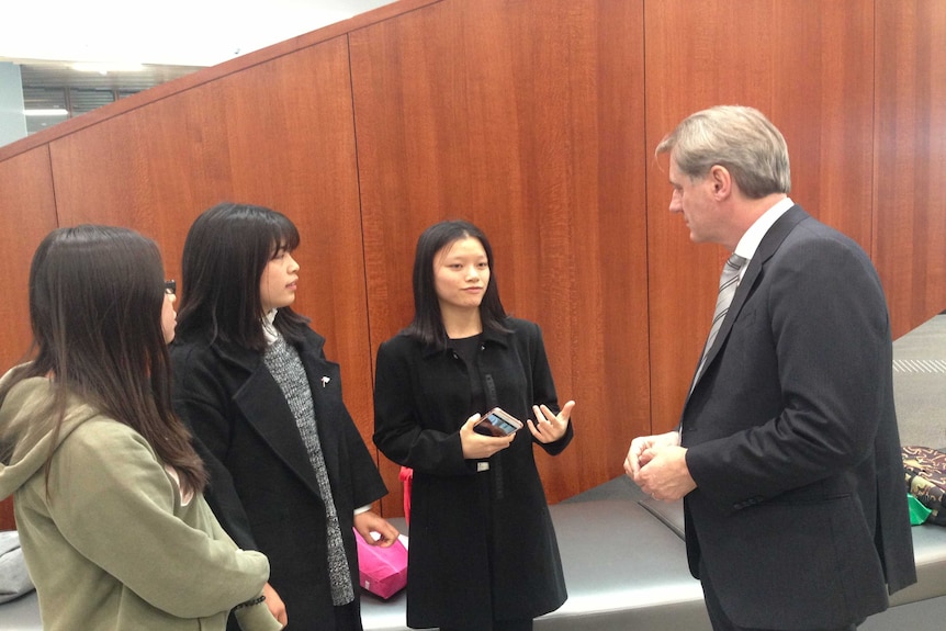 Sydney University's Business School, Professor Greg Whitwell speaking with three Asian women.