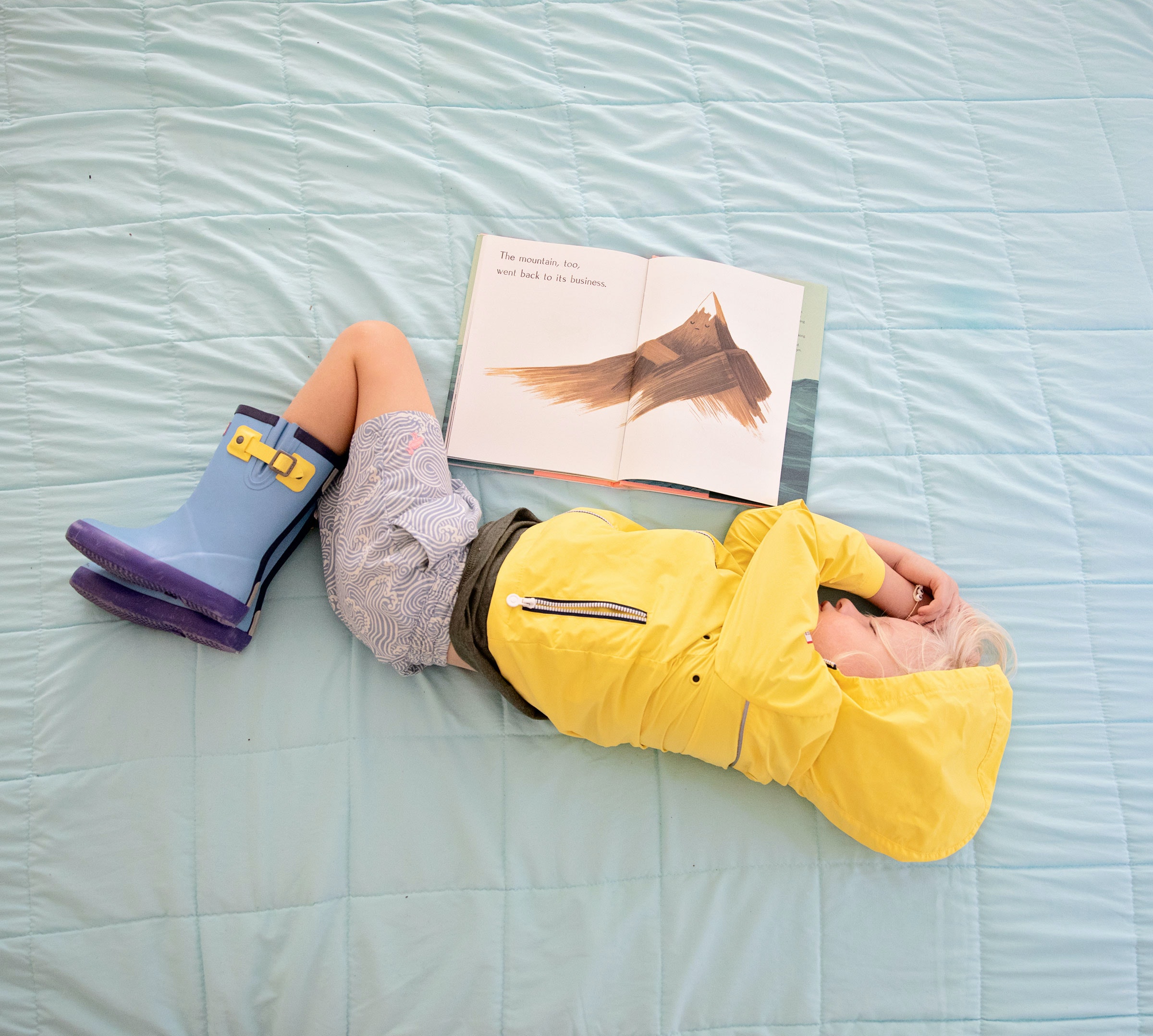 Child sleeping on a bed with an open book by his side. 