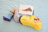 Child sleeping on a bed with an open book by his side. 