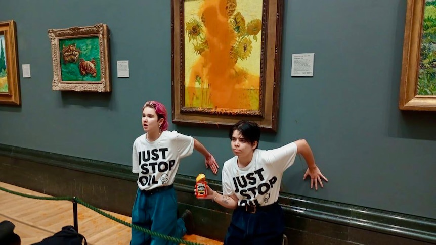 Two people kneel below a Van Gogh painting. 