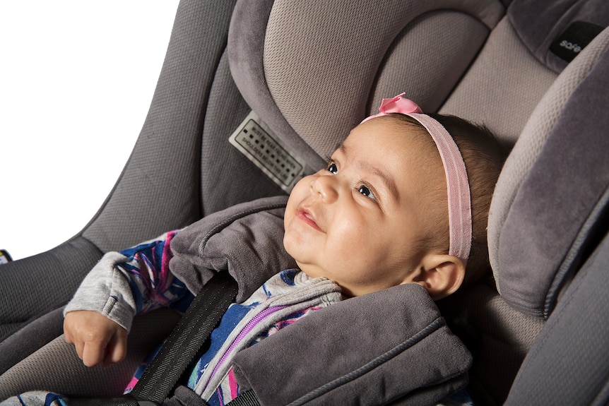 A baby smiling in a car seat.