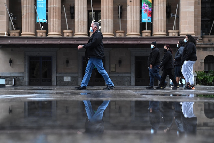 People wearing face masks walking through King George Square during COVID-19 lockdown in Brisbane.