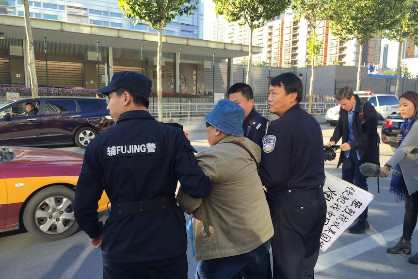 Chinese police escort an anti-American protester away from the US embassy in Beijing