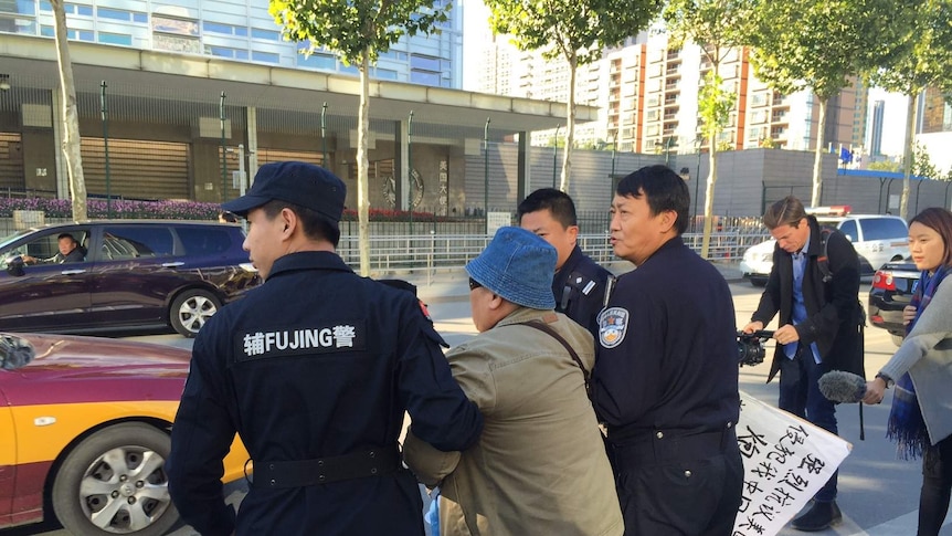 Chinese police escort an anti-American protester away from the US embassy in Beijing