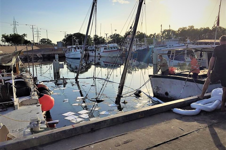 Two masts appear out of the water in a marina in the early morning.