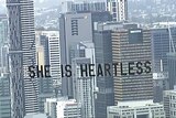 Banner says "she is heartless" seen over Brisbane sky line.