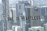 Banner says "she is heartless" seen over Brisbane sky line.