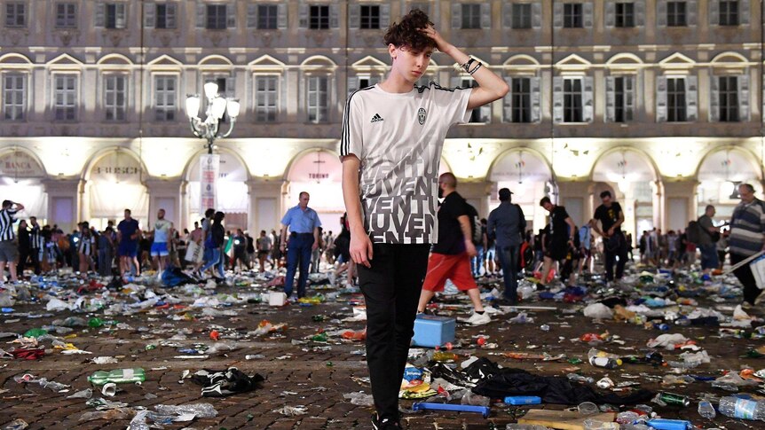 A Juventus fan stands among rubbish in San Carlo's Square.