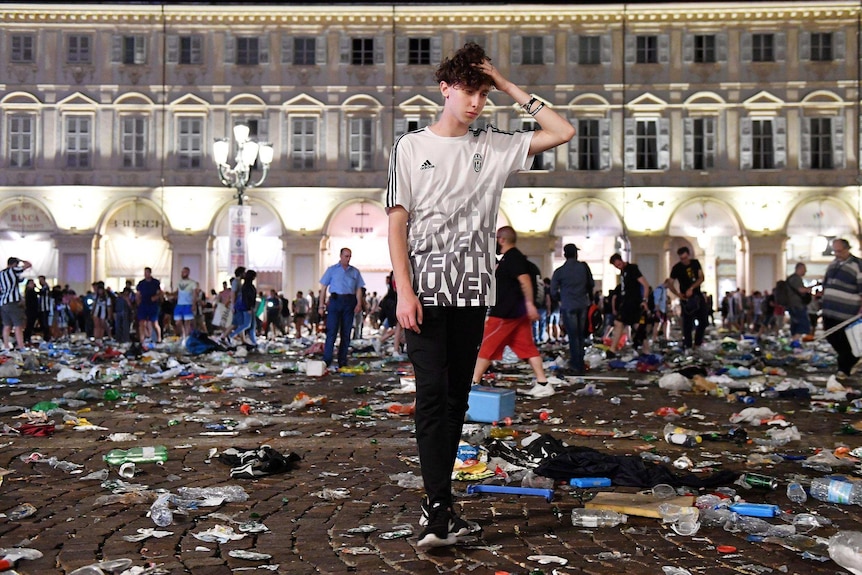 A Juventus fan stands among rubbish in San Carlo's Square.