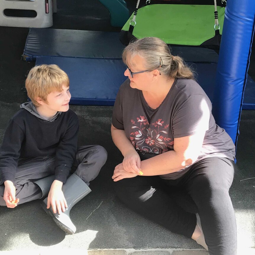 Martina McNeill smiles with son Alex sitting near a playground.