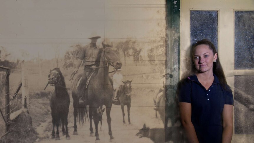 Brooke Hooton stands against an old farming photo projected onto a wall.