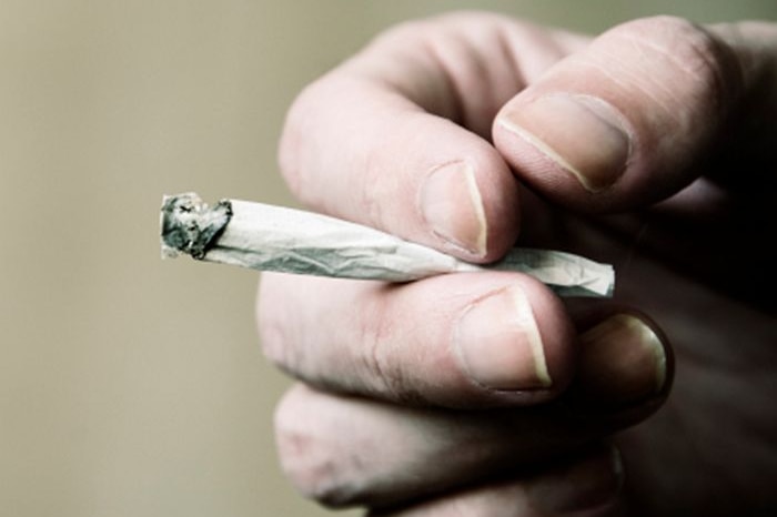 A person's hand holding a joint